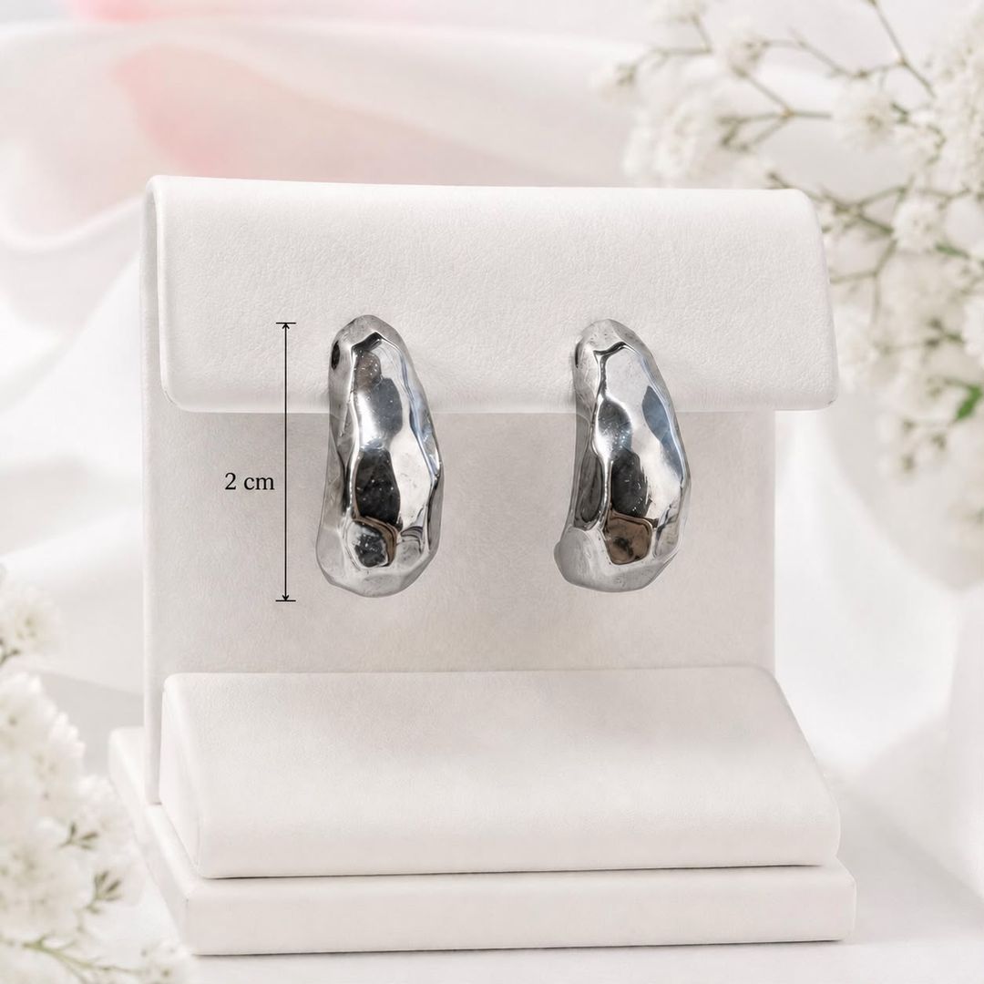 Aretes MElegantes aretes de diseño orgánico e irregular, con acabado plateado brillante que les da un estilo moderno y sofisticado. Su forma escultórica los convierte en un accesorio llamativo, ideal 